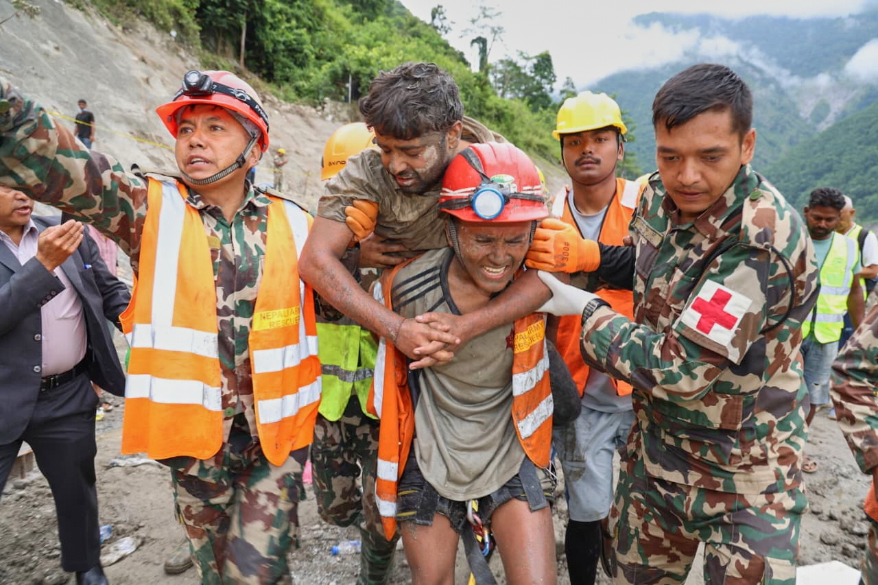 In this photo provided by the Nepal Army, soldiers rescue a worker alive from a tunnel during an ongoing operation at the Trishuli-3A hydropower project in Nepal